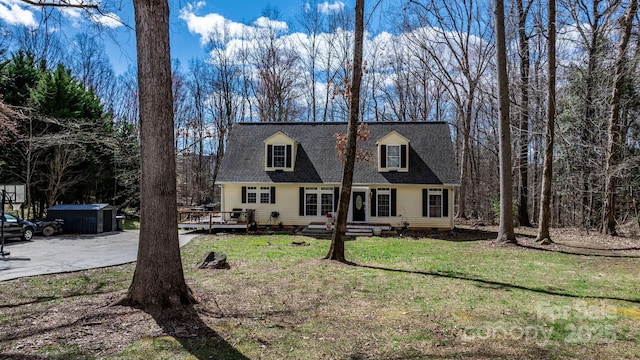 cape cod-style house featuring an outbuilding, a front lawn, roof with shingles, a wooden deck, and crawl space