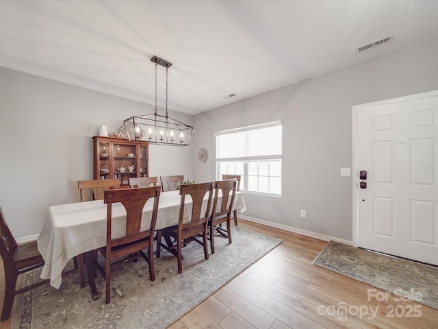 dining room with a chandelier, visible vents, baseboards, and wood finished floors