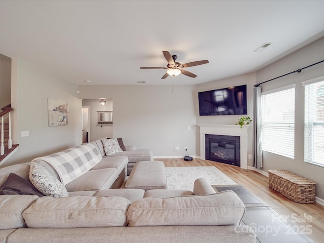 living room with visible vents, plenty of natural light, a ceiling fan, and light wood-style floors