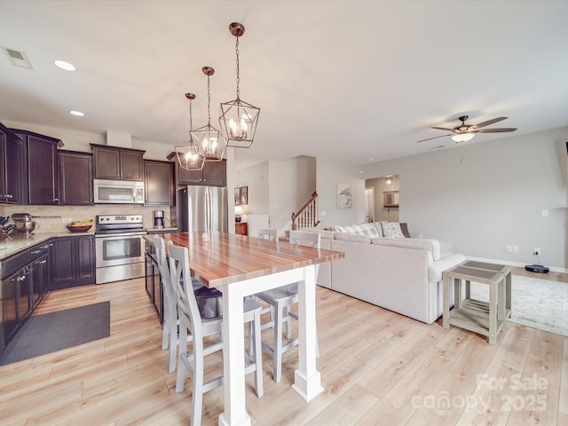 kitchen with visible vents, dark brown cabinetry, decorative backsplash, light wood-style floors, and stainless steel appliances