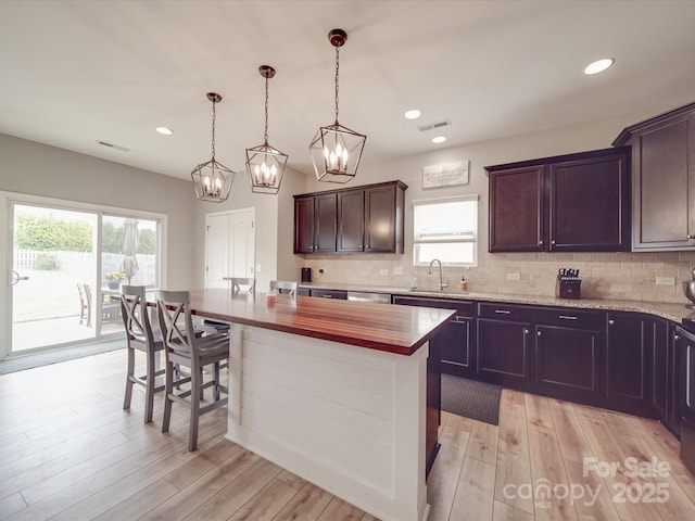 kitchen featuring tasteful backsplash, light wood-style flooring, a notable chandelier, and visible vents