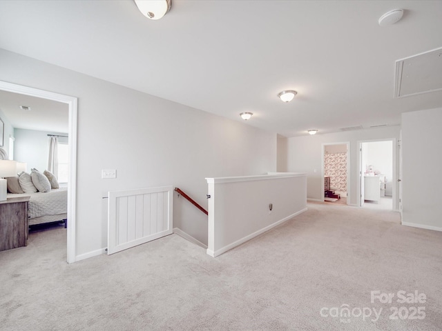 carpeted spare room with attic access and baseboards