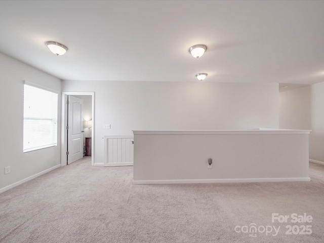 spare room with baseboards and light carpet