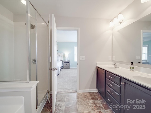 full bathroom featuring ensuite bathroom, a sink, a shower stall, double vanity, and baseboards