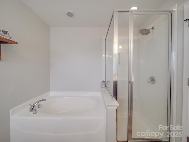 bathroom featuring a bath and a shower stall