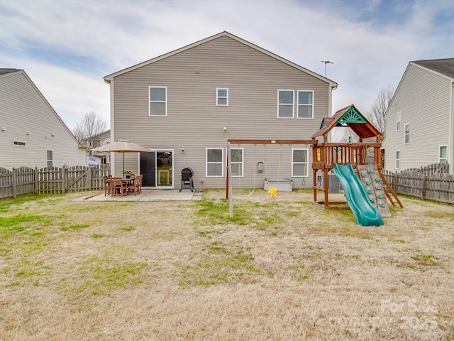 back of property with a patio, a playground, a yard, and a fenced backyard