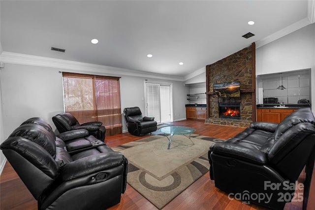 living area featuring baseboards, dark wood finished floors, a fireplace, ornamental molding, and vaulted ceiling