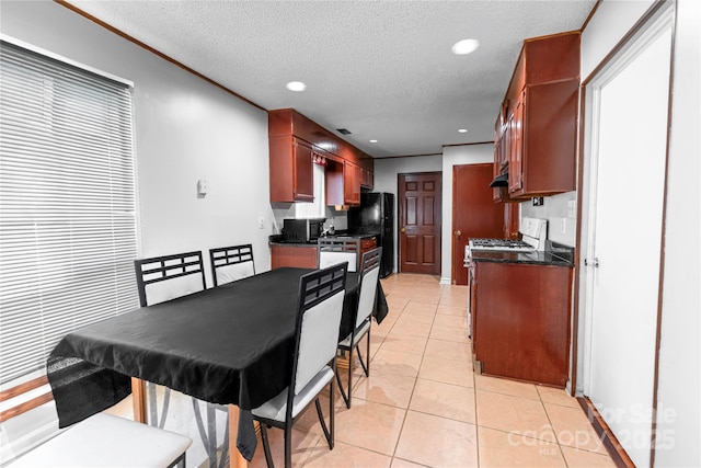 kitchen featuring dark countertops, recessed lighting, freestanding refrigerator, light tile patterned flooring, and a textured ceiling