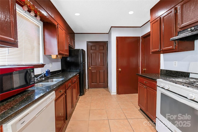 kitchen featuring ornamental molding, light tile patterned floors, dark stone countertops, white appliances, and a sink