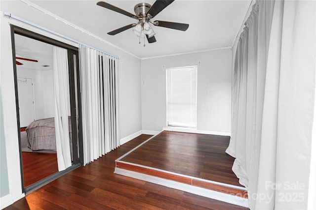 unfurnished bedroom featuring a ceiling fan, crown molding, wood finished floors, and baseboards