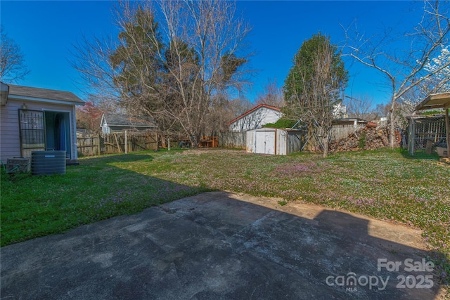 view of yard featuring an outbuilding, central AC unit, a fenced backyard, and a storage shed