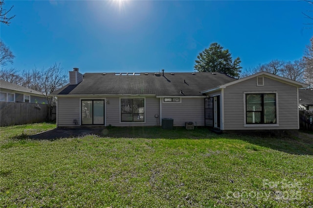 rear view of property featuring cooling unit, a lawn, a chimney, and fence