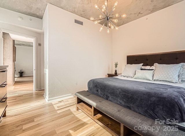 bedroom with visible vents, baseboards, an inviting chandelier, and light wood finished floors