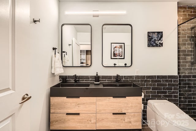 bathroom featuring double vanity, toilet, tile walls, and a sink