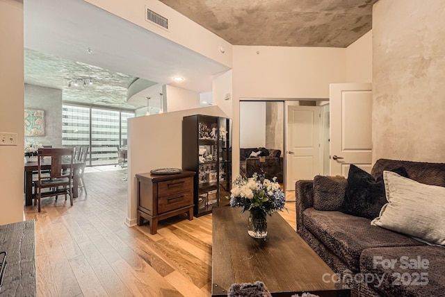 living area featuring floor to ceiling windows, light wood-style flooring, and visible vents