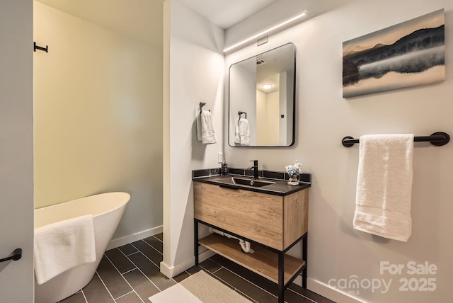 bathroom featuring baseboards, a freestanding bath, and vanity