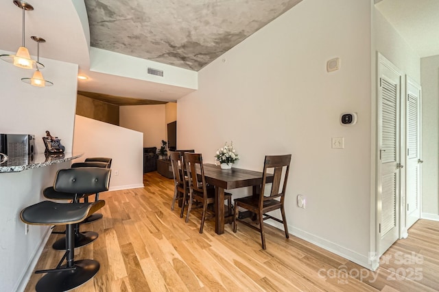 dining room with light wood finished floors, visible vents, and baseboards