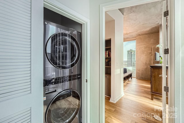 laundry area with light wood-type flooring, stacked washer and dryer, and laundry area