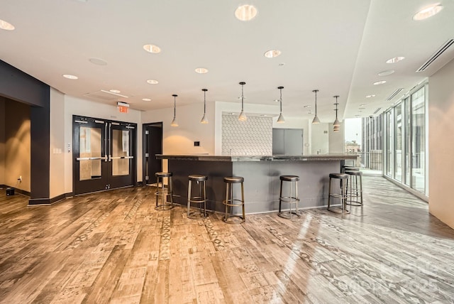 kitchen featuring visible vents, light wood-style floors, dark countertops, and a breakfast bar area