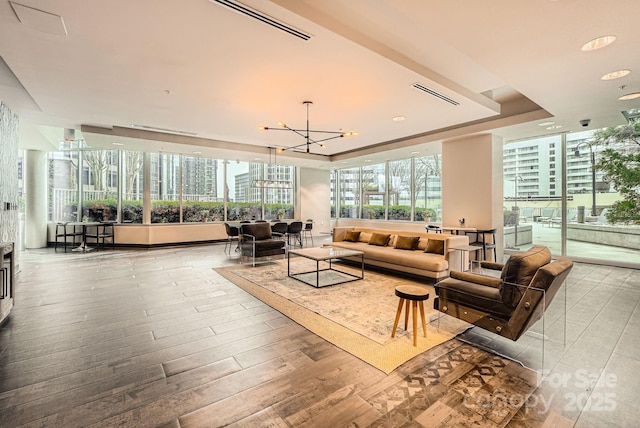 interior space featuring a wall of windows, wood finished floors, visible vents, a tray ceiling, and a chandelier