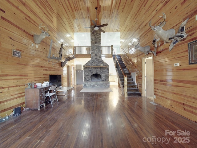 unfurnished living room with stairway, wood-type flooring, wooden walls, and wooden ceiling