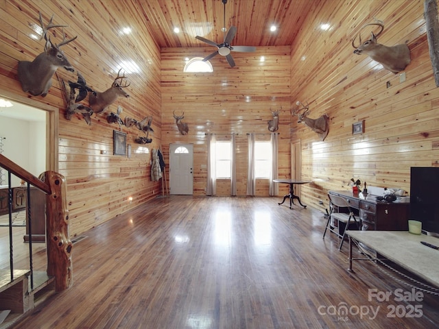 office space with wood finished floors, a high ceiling, ceiling fan, wood walls, and wooden ceiling