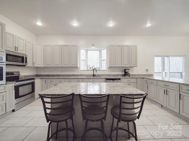 kitchen featuring light tile patterned flooring, stainless steel appliances, a kitchen bar, and a sink