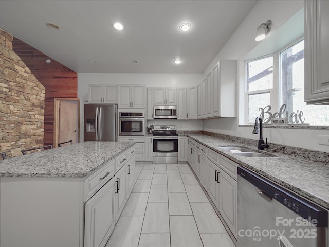 kitchen featuring light tile patterned floors, light stone countertops, a kitchen island, a sink, and stainless steel appliances