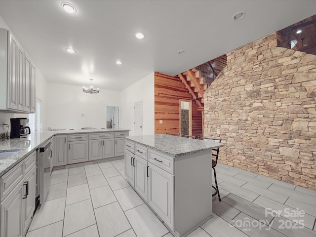 kitchen with light stone countertops, a notable chandelier, dishwasher, and a peninsula