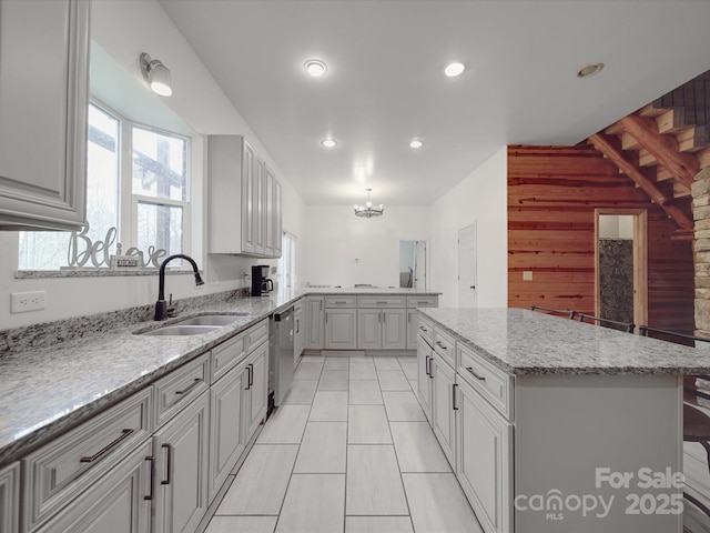 kitchen with a sink, a center island, a peninsula, an inviting chandelier, and dishwasher