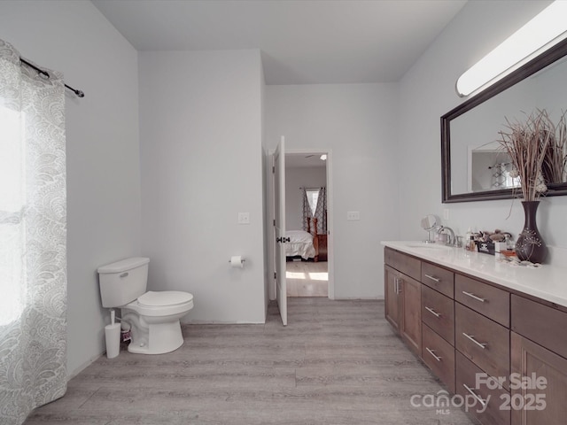 full bathroom with toilet, ensuite bath, wood finished floors, and vanity