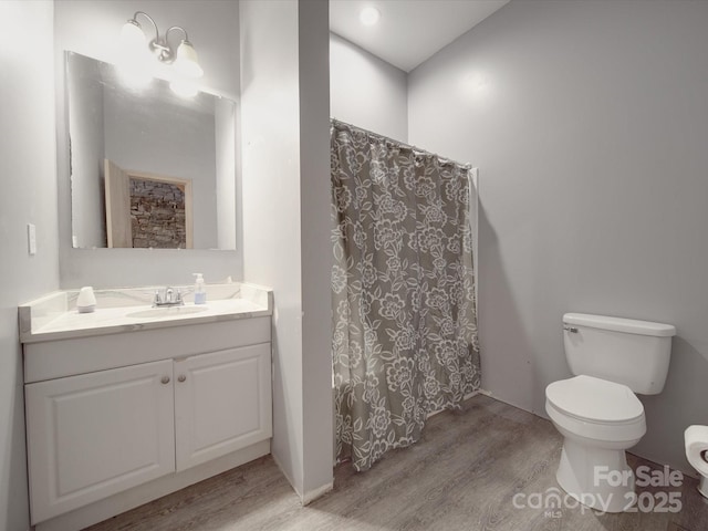 bathroom with vanity, curtained shower, toilet, and wood finished floors