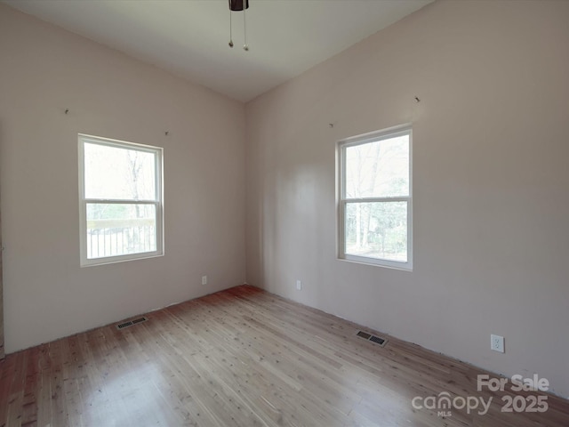 spare room featuring a wealth of natural light, visible vents, and wood finished floors