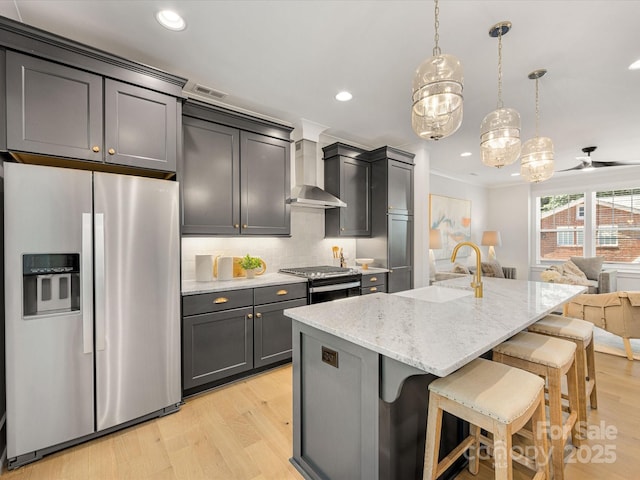 1409 Kenilworth Ave, Charlotte, NC 28203 - kitchen featuring appliances with stainless steel finishes, wall chimney exhaust hood, light wood-style flooring, a kitchen breakfast bar, and recessed lighting