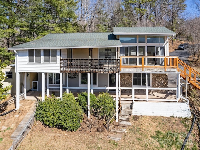 rear view of property with stairway and a shingled roof