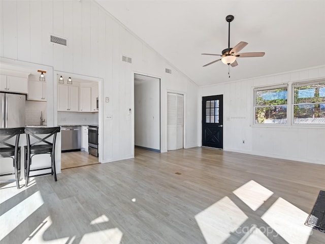 unfurnished living room featuring visible vents, light wood-type flooring, ceiling fan, and a sink