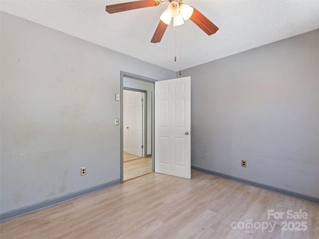 empty room with baseboards, a textured ceiling, wood finished floors, and a ceiling fan