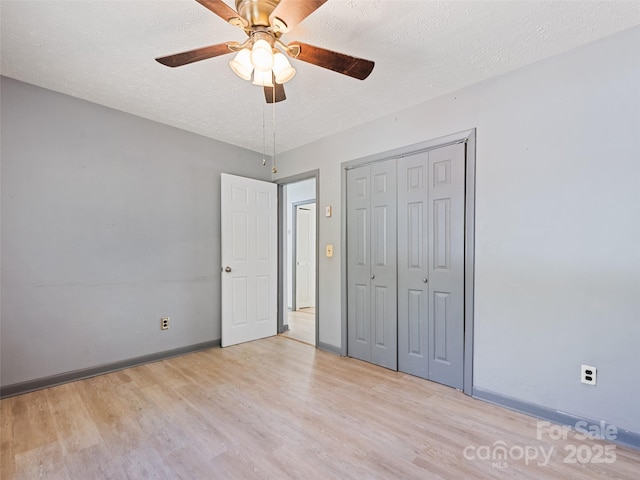 unfurnished bedroom with baseboards, light wood-style floors, a closet, and a textured ceiling