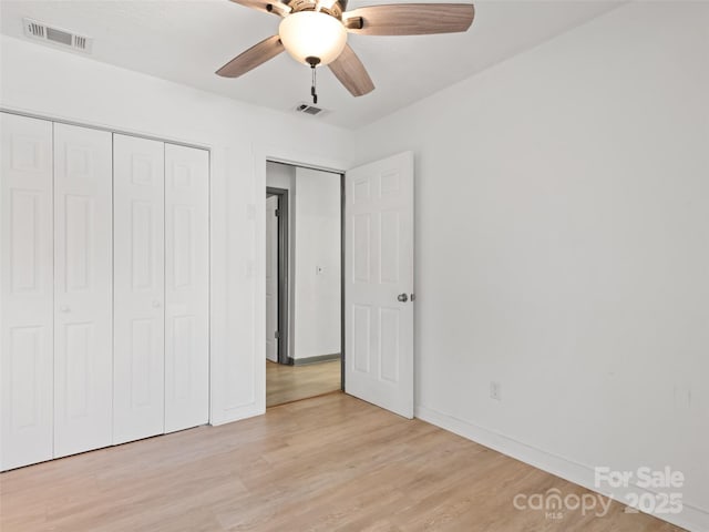 unfurnished bedroom featuring light wood finished floors, visible vents, ceiling fan, and a closet