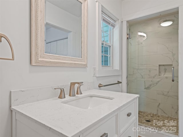 full bath featuring a marble finish shower and vanity