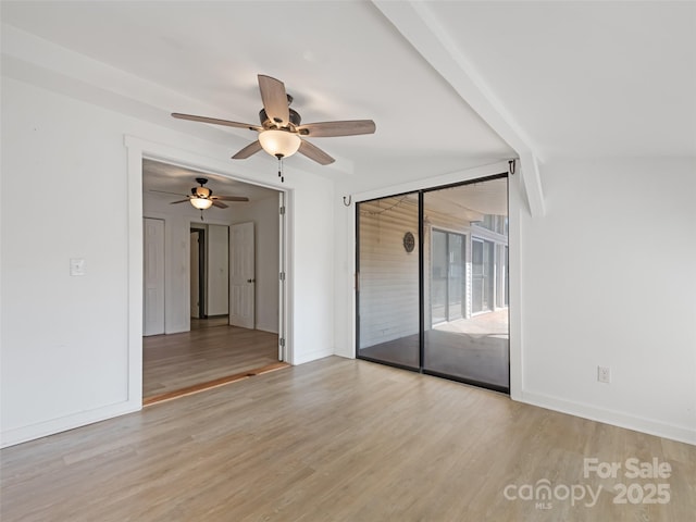 spare room with a ceiling fan, wood finished floors, and baseboards