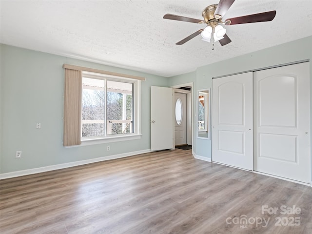 unfurnished bedroom featuring ceiling fan, baseboards, wood finished floors, a closet, and a textured ceiling