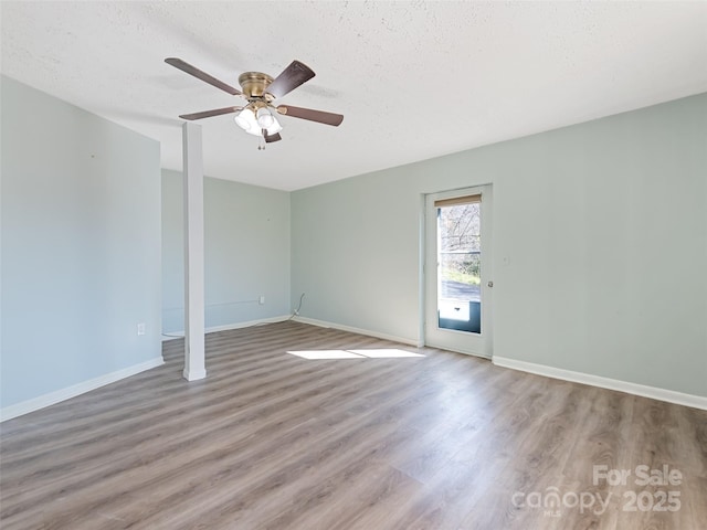 unfurnished room with a textured ceiling, baseboards, ceiling fan, and wood finished floors