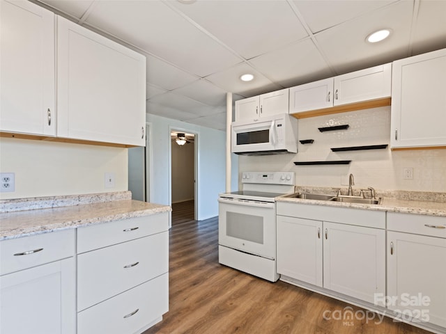 kitchen with tasteful backsplash, wood finished floors, white cabinets, white appliances, and a sink