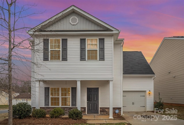 view of front of house featuring a porch, stone siding, driveway, and a garage