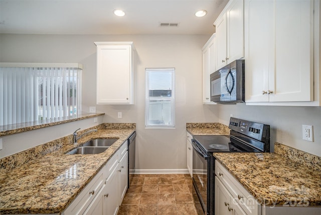 kitchen with baseboards, a peninsula, a sink, black appliances, and white cabinets