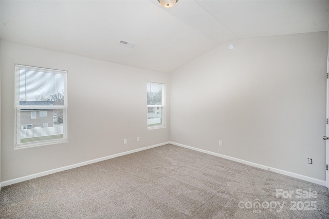 carpeted empty room featuring lofted ceiling, baseboards, visible vents, and a wealth of natural light