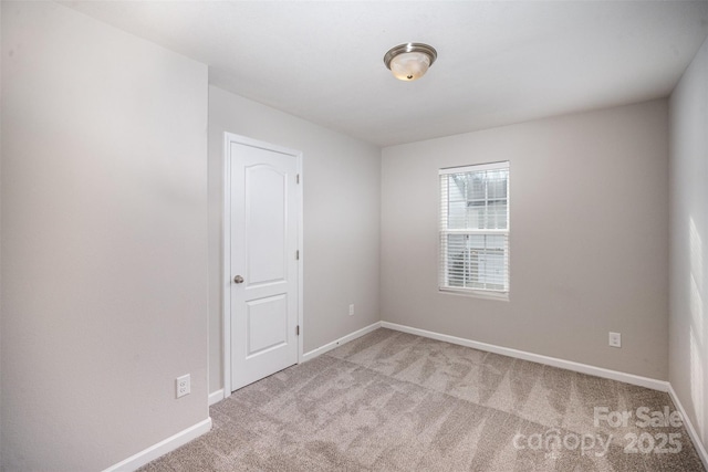 unfurnished room featuring baseboards and light colored carpet