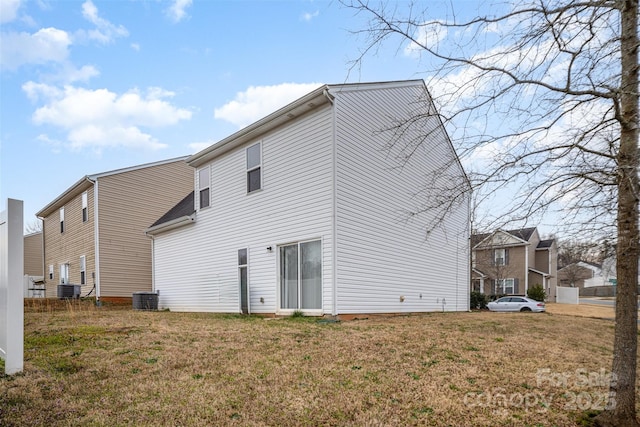 back of property featuring central air condition unit and a yard