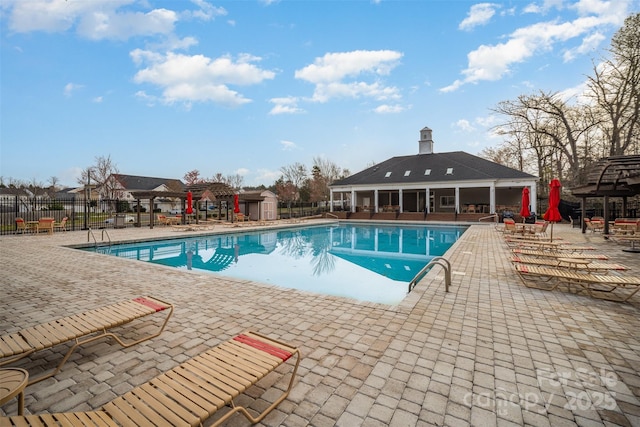 pool featuring fence, an outdoor structure, and a patio area